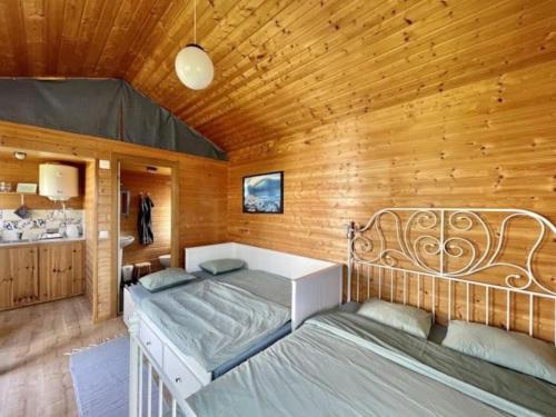 a bedroom with two beds and a wooden wall at Da Silva Surfcamp - Tiny House Jorgina in Lourinhã