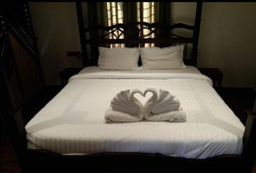 a white bed with a heart shaped towel on it at Pushkar Guest House in Pushkar