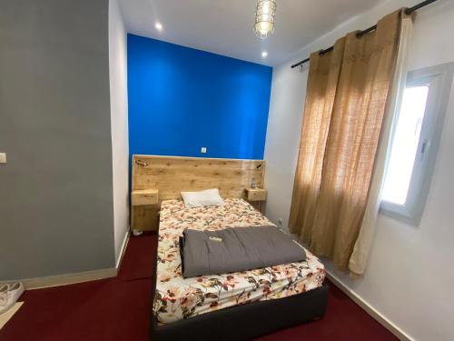 a bedroom with a bed and a blue wall at Studio privé meublé et équipé in Dakar