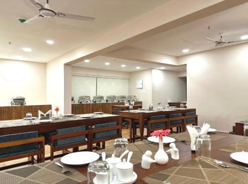 a dining room with tables and chairs and a large screen at The Habitat Suites in Guruvāyūr
