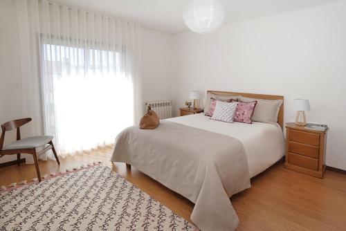 a white bedroom with a bed and a chair at Guimarães Downtown by LuxiStay in Guimarães
