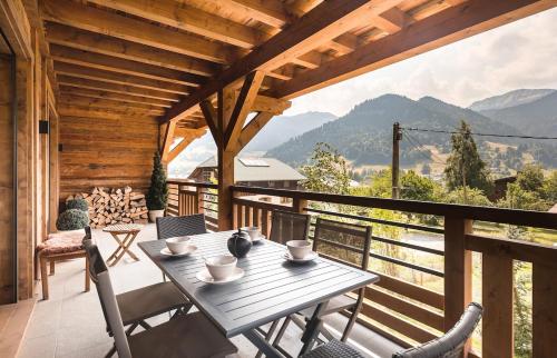 a wooden deck with a table and chairs on a balcony at A brand new apartment in a calm environment in Praz-sur-Arly