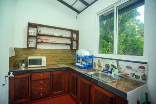 a kitchen with a sink and a microwave at Villa Kavee in Galle