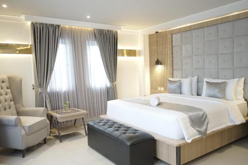 a bedroom with a large white bed and a chair at 1O1 URBAN Jakarta Thamrin in Jakarta