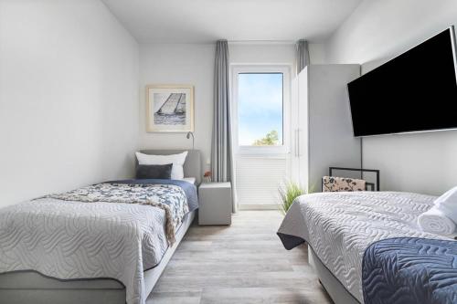 een slaapkamer met 2 bedden en een flatscreen-tv bij BeachTerraceOne - EG, Meerblick, Terrasse, Kamin, Sauna in Olpenitz