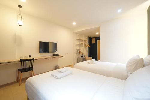 a hotel room with two beds and a tv at Alto Hotel M in Mae Sot