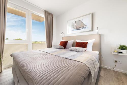 1 dormitorio con 1 cama grande y 2 ventanas en BeachLoungeThree- 1 OG, Meerblick, Balkon, Kamin, Sauna, en Olpenitz