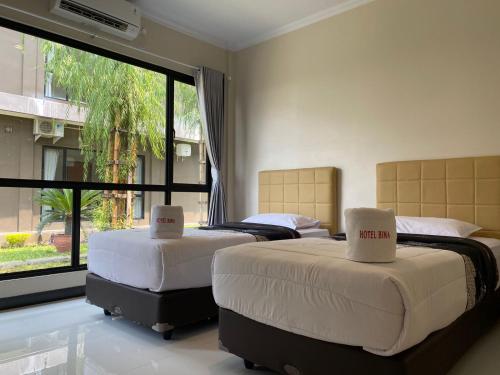 two beds in a room with a large window at Hotel Bima Majalengka in Majalengka