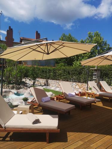 a group of lounge chairs and an umbrella on a deck at Makis Nest Apart-Hotel in Vourvourou