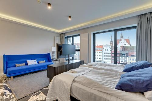 a bedroom with a blue couch and a large window at Comfort Apartments Deo Plaza in Gdańsk