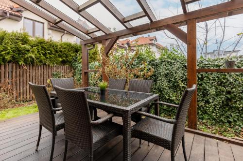 una mesa y sillas en una terraza de madera con pérgola en Spacious Two-Story 4-Bedroom House with Parking and Garden in Warsaw by Renters, en Varsovia