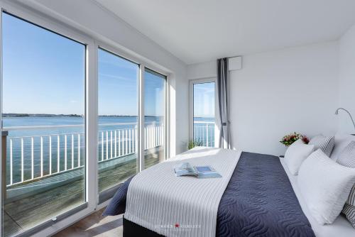 1 dormitorio con 1 cama y balcón con vistas al océano en Ostseewind: Wasserblick, finnische Sauna, Whirlwanne, Kamin, 2 Parkplaetze en Kappeln