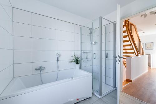 ein weißes Bad mit einer Badewanne und einer Dusche in der Unterkunft Ferienhaus Nis Randers in Olpenitz