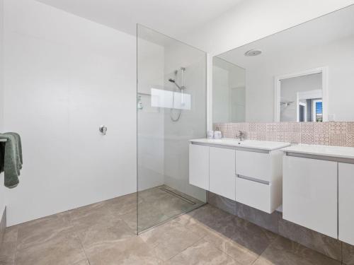 a white bathroom with a sink and a mirror at The Beachside Sanctuary -500m from Beach with Pool & Heated Spa in Casuarina