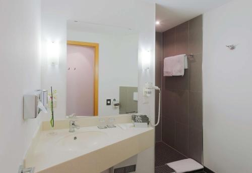 ein Badezimmer mit einem Waschbecken und einem großen Spiegel in der Unterkunft Hotel Dusseldorf Krefeld Affiliated by Meliá in Krefeld