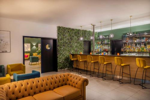 eine Lobby mit einer Bar mit gelben Stühlen in der Unterkunft Hotel Dusseldorf Krefeld Affiliated by Meliá in Krefeld
