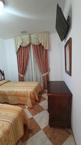 a hotel room with two beds and a television at Hostal Algaidas in Villanueva de Algaidas