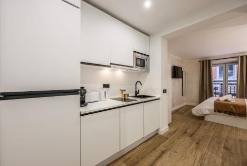 een keuken met witte kasten en een bed in een kamer bij Asequible apartamento a pasos de Callao in Madrid