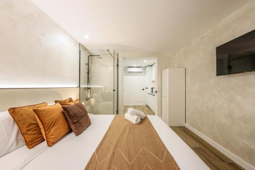 マドリードにあるAsequible apartamento a pasos de Callaoのベッドルーム1室(オレンジ色の枕とテレビ付)