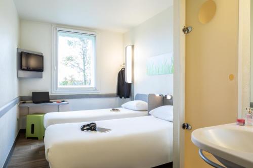 a hotel room with two beds and a sink at ibis budget Roissy CDG Paris Nord 2 in Roissy-en-France