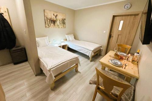Cette petite chambre comprend deux lits et une table. dans l'établissement Olszyna Pod Brzozą, à Olszyna