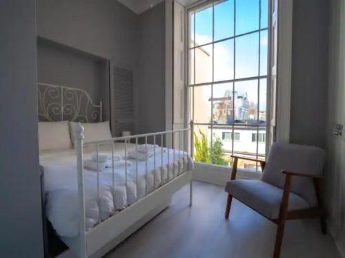 a bedroom with a bed and a chair and a window at Pass the Keys Lovely bright and central apartment in Cheltenham in Cheltenham