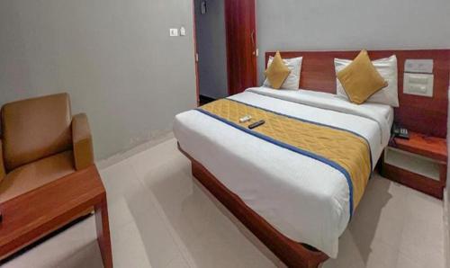 a bedroom with a large bed and a chair at FabHotel Gateway Suites in Bangalore