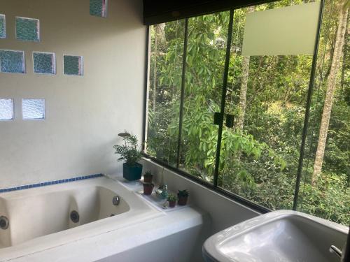 baño con bañera y ventana grande en Shanti Yoga Forest House, en Florianópolis