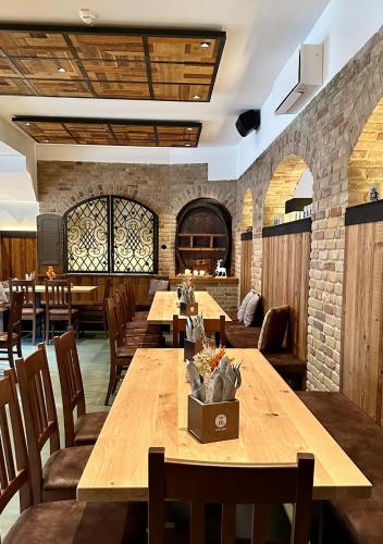 a restaurant with wooden tables and chairs and a brick wall at Hotel-Hofbräu am Stadtring in Nordhorn