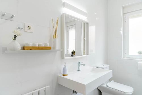 a white bathroom with a sink and a mirror at Casa la Fontana in Granada