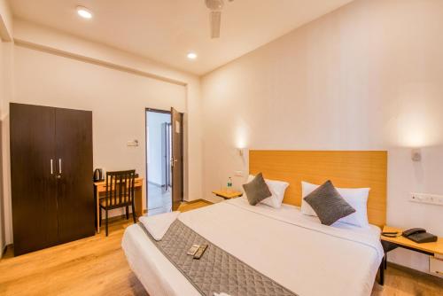 ポンディシェリにあるIyla Apart Hotelの木製のヘッドボードが付いた大きな白いベッドのある寝室