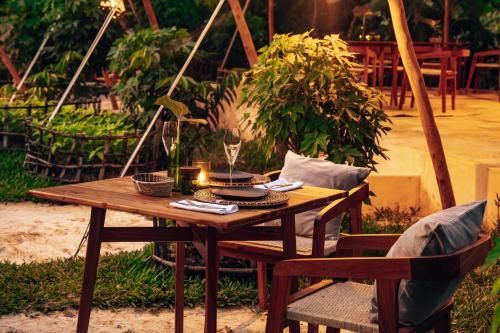 a wooden table and chairs with a candle on it at Ycona Eco-Luxury Resort, Zanzibar in Dikoni