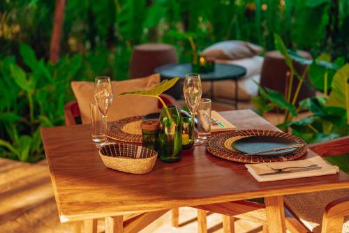 a wooden table with wine glasses and plates on it at Ycona Eco-Luxury Resort, Zanzibar in Dikoni