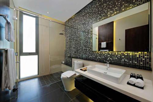 a bathroom with a sink and a toilet and a mirror at Deluxe Beach Villas by Danatrip in Da Nang