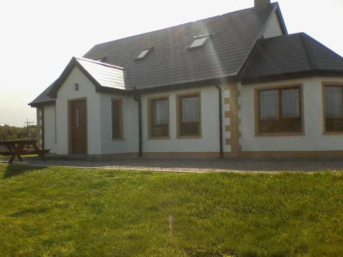 a small white house with a table in front of it at The lake house in Gweedore