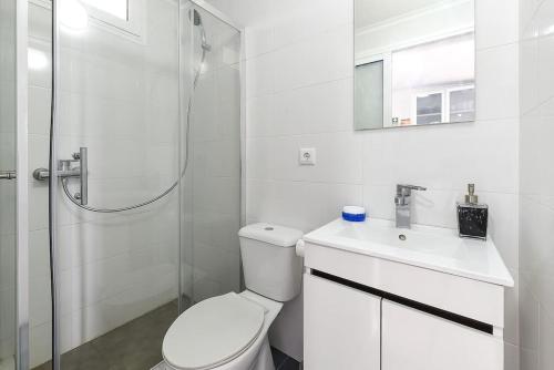 a white bathroom with a toilet and a shower at Casa do Mar in Funchal