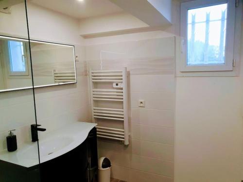 une salle de bain blanche avec un lavabo et un miroir dans l'établissement Appartement indépendant en rdc dans propriété, à La Madrague