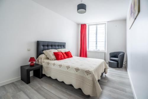 a bedroom with a bed with red pillows and a chair at Coeur de Ville 1 & 2 in Jonzac