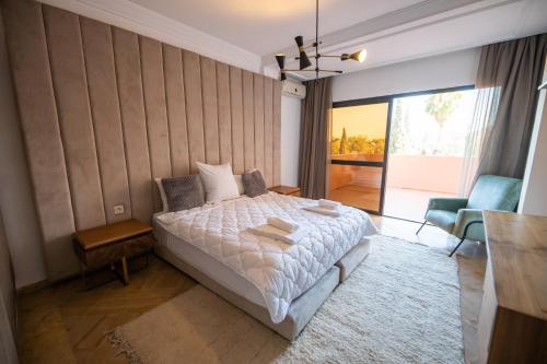 een slaapkamer met een bed, een tafel en een stoel bij Al Destino Apartment Luxury Marrakech in Marrakesh