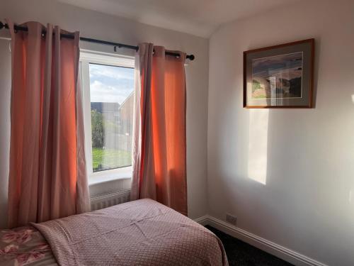 a bedroom with an orange curtain and a window at The Genesis one in Manchester