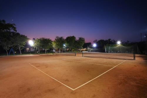 a tennis court at night with lights on at The Chitvan Resort in Ajmer