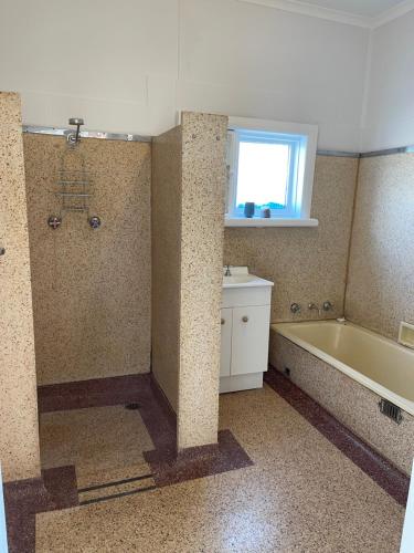 uma casa de banho com uma banheira e uma janela em Apartment 1 on Oxide em Broken Hill
