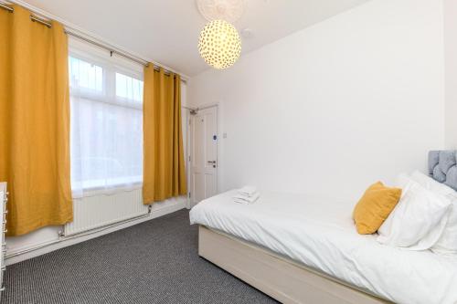 a bedroom with a bed and a window with yellow curtains at Stoneley Stays by Urban Hazelnut in Crewe