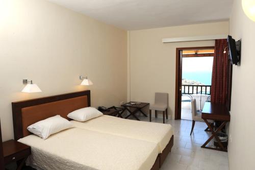 1 dormitorio con cama, escritorio y balcón en Porto Delfino Retreat, en Kapsálion