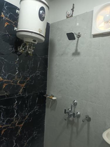 baño con ducha y secador de pelo en la pared en KK PALACE HOMESTAY AND GARDEN, en Kota