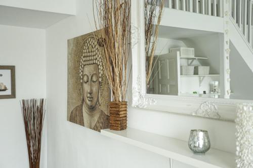 a mirror on a shelf with a picture of a head at Secret Seaside Retreat in Kent
