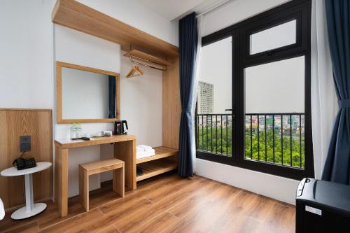 a room with a large window and a desk with a table at Haven Hut Riverside Hotel in Ho Chi Minh City