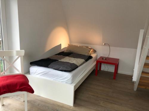 a small bed in a room with a red table at Schlei 48 in Borgwedel