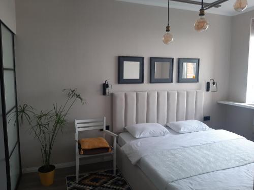 une chambre avec un lit blanc et une plante dans l'établissement Двухкомнатная квартира на самом берегу реки, à Pavlodar