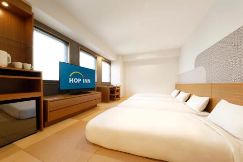 a hotel room with two beds and a flat screen tv at Hop Inn Kyoto Shijo Omiya in Kyoto